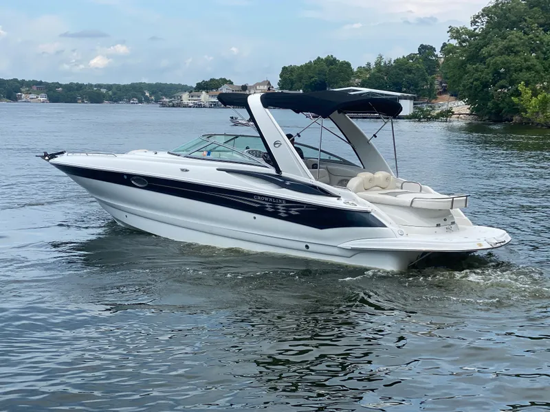 Slide: The Image of 2006 Crownline 320 LS boat cruising on a scenic lake with lush greenery. - 6