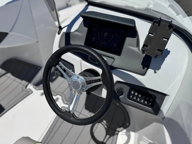 Slide: The Image of 2023 Tahoe 210 Si boat dashboard with steering wheel and digital display. - 23