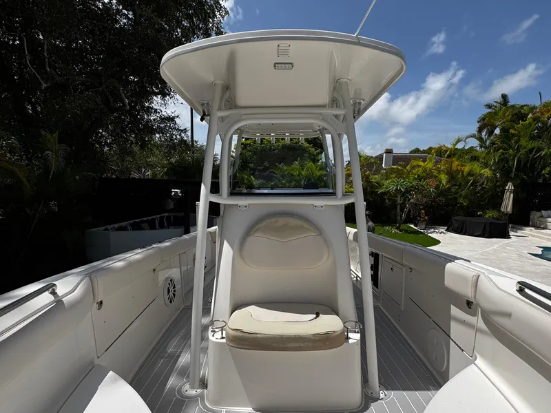 Slide: The Image of 2016 Robalo R260 Center Console boat with seating, surrounded by lush greenery and blue sky. - 16