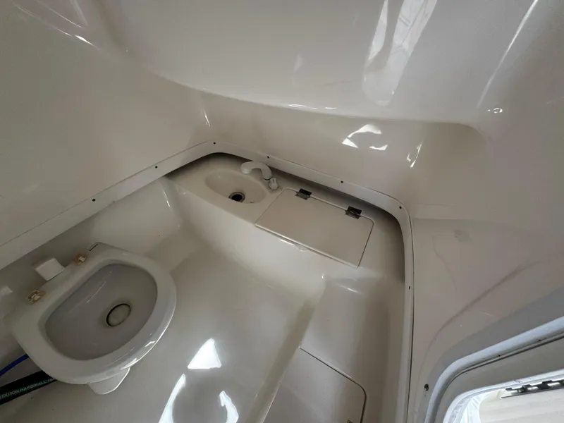 Slide: The Image of Interior of 2016 Robalo R260 Center Console boat featuring a compact marine toilet. - 23