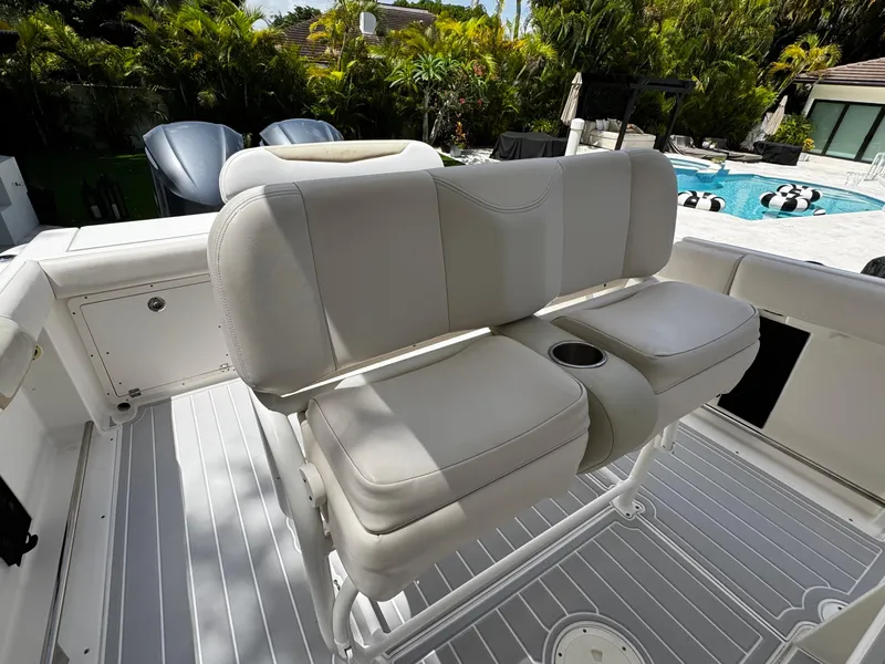 Slide: The Image of 2016 Robalo R260 Center Console boat with cushioned seating and cup holder, near a poolside. - 25