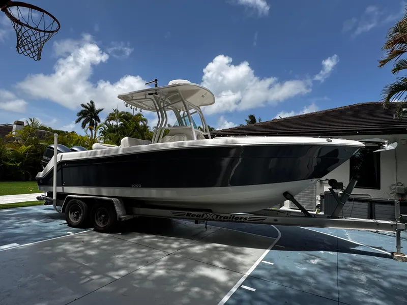 Slide: The Image of 2016 Robalo R260 Center Console boat on trailer, parked outdoors under blue sky. - 4