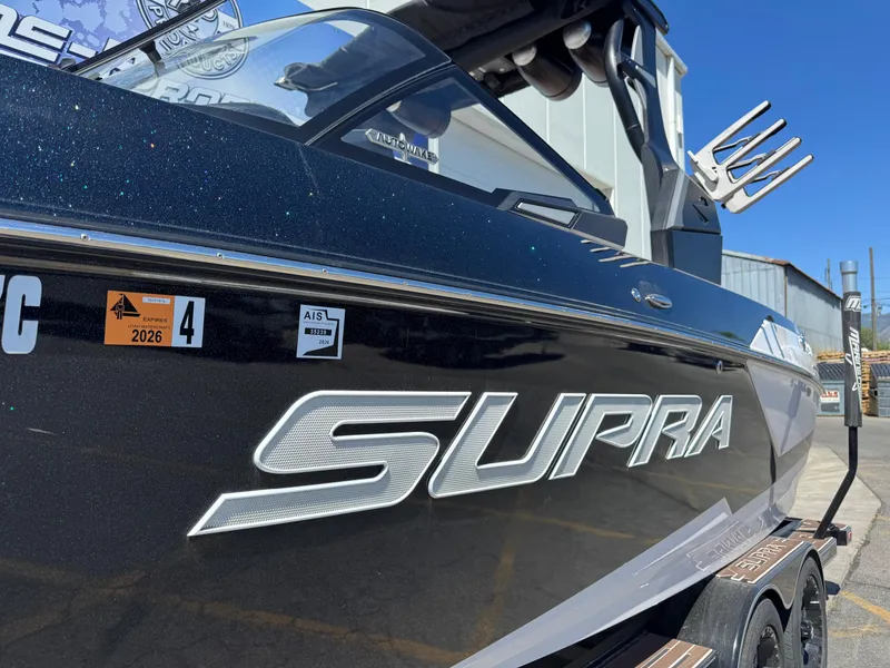 Slide: The Image of 2021 Supra SL 550 boat with sleek black design and visible registration stickers. - 3