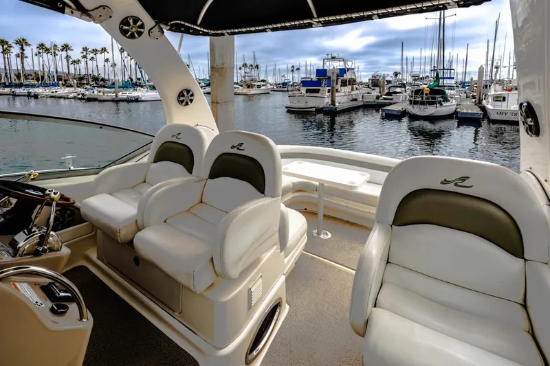 Slide: The Image of 2006 Sea Ray 340 Sundancer interior with plush seating, overlooking a marina with docked boats. - 16