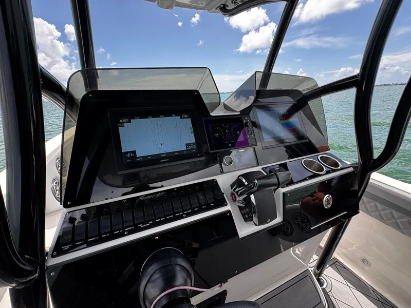 Slide: The Image of 2023 Avanti 36 boat dashboard with navigation screens and controls, set against a scenic ocean backdrop. - 23