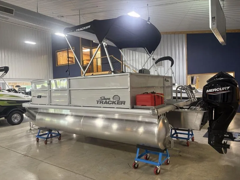 Slide: The Image of 2026 Sun Tracker PARTY BARGE® 16 DLX pontoon boat in showroom with Mercury outboard motor. - 5