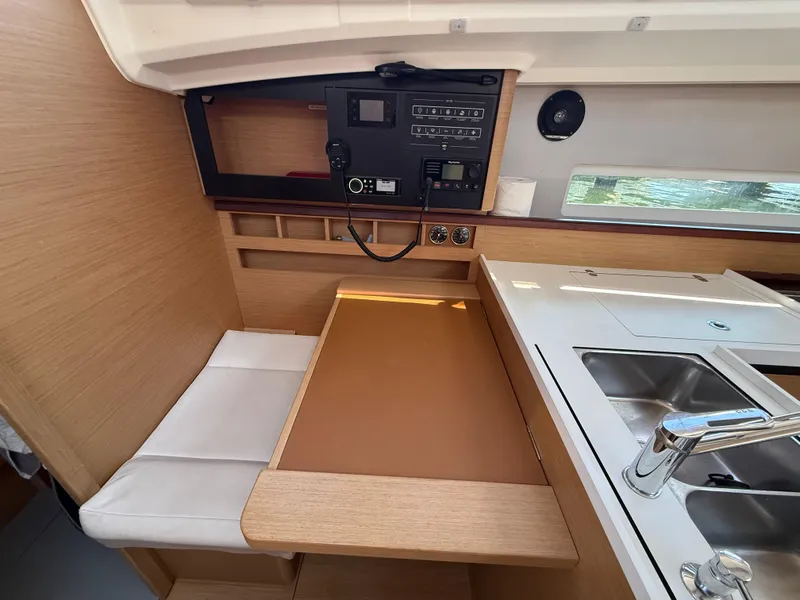 Slide: The Image of Interior of 2021 Jeanneau Sun Odyssey 410 yacht, featuring a compact kitchen and seating area. - 13