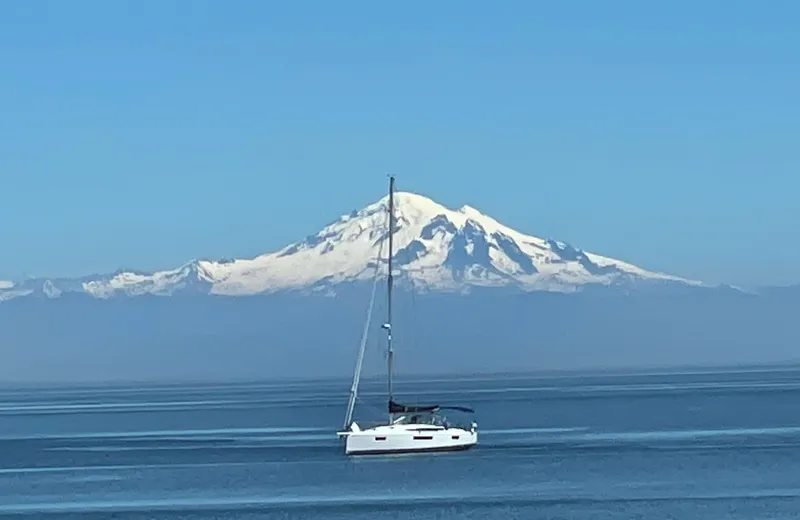 Slide: The Image of Sailboat Jeanneau Sun Odyssey 410 on calm sea with snow-capped mountain backdrop. - 15