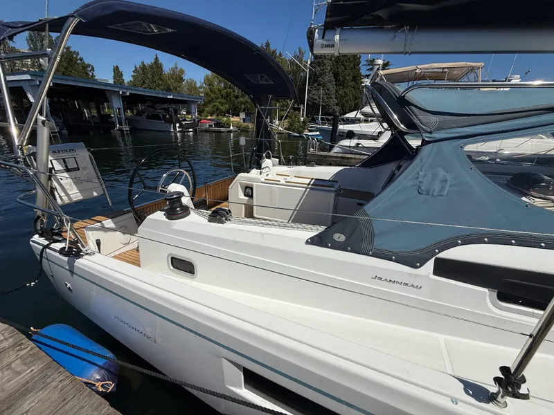 Slide: The Image of 2021 Jeanneau Sun Odyssey 410 sailboat docked at marina, featuring sleek design and blue canopy. - 25