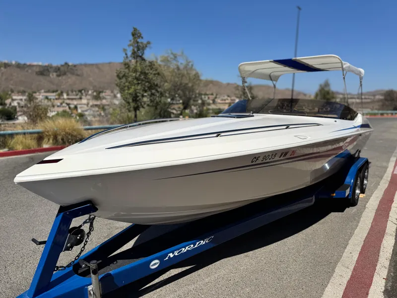 Slide: The Image of 1998 Nordic 25 Scandia boat on trailer, parked outdoors under clear blue sky. - 3