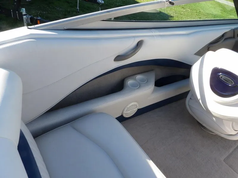 Slide: The Image of Interior of a 2004 Crownline 202BR boat, featuring white and blue seating. - 13