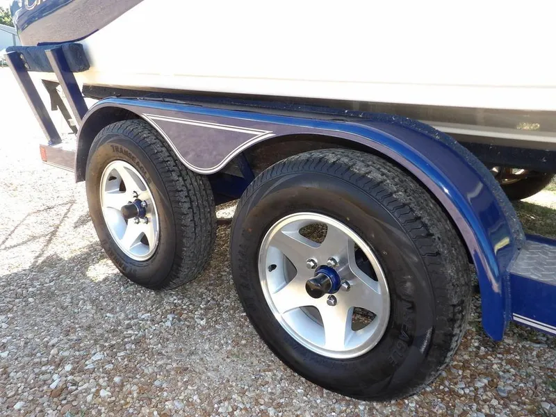 Slide: The Image of Trailer wheels of a 2004 Crownline 202BR boat on gravel surface. - 34