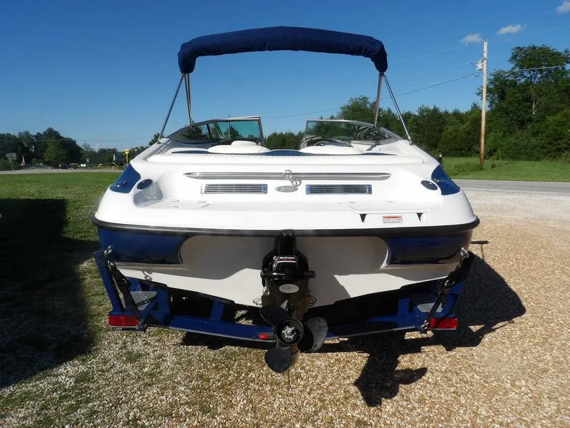 Slide: The Image of 2004 Crownline 202BR boat, rear view, on trailer, with blue canopy, parked outdoors. - 5