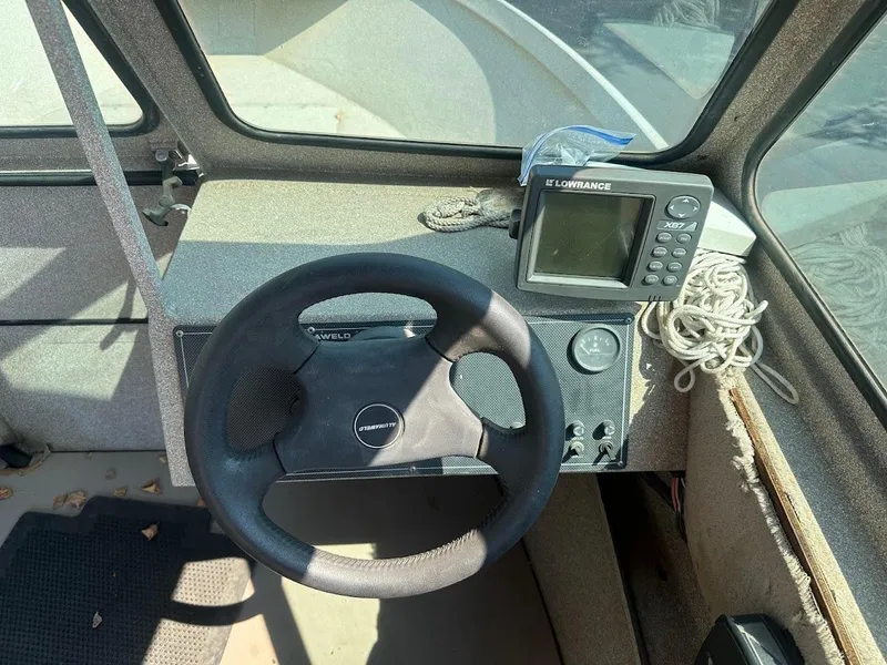 Slide: The Image of 2003 Alumaweld Stryker boat dashboard with steering wheel and Lowrance X67 fish finder. - 17