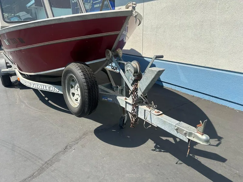 Slide: The Image of 2003 Alumaweld Stryker boat on trailer, parked on pavement, red hull, visible trailer hitch. - 4