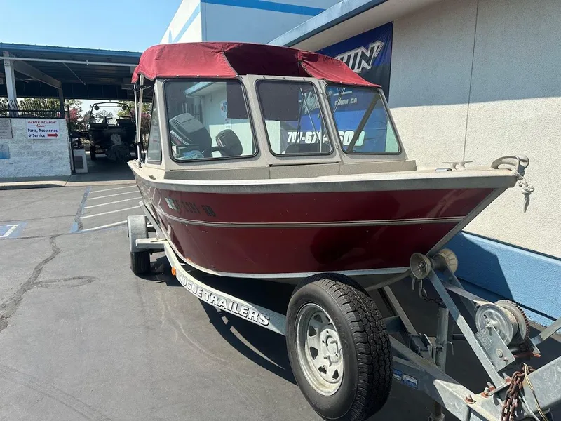 Slide: The Image of 2003 Alumaweld Stryker boat with red canopy on trailer, parked outside a building. - 5