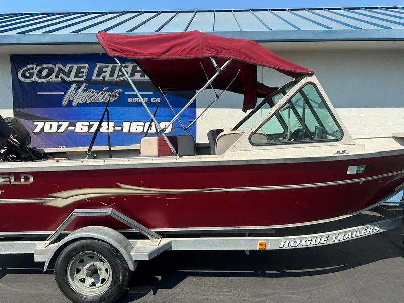 Slide: The Image of 2003 Alumaweld Stryker boat with maroon canopy on Rogue trailer, parked outside. - 6