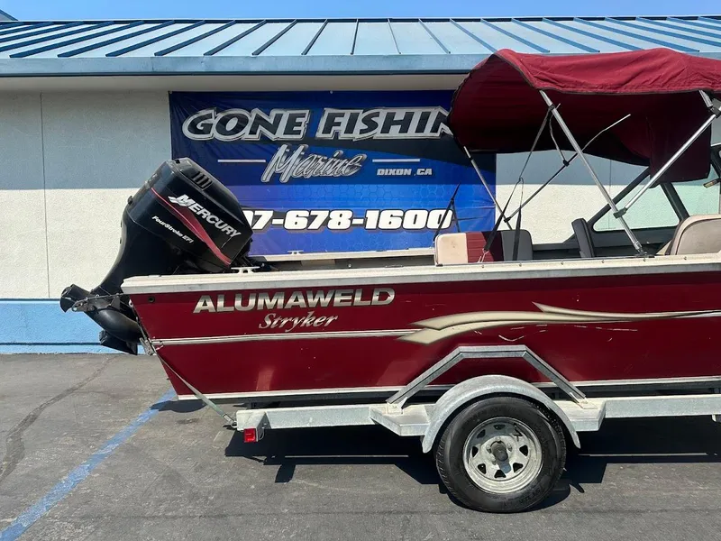 Slide: The Image of 2003 Alumaweld Stryker boat with Mercury engine, parked outside a marine shop. - 7