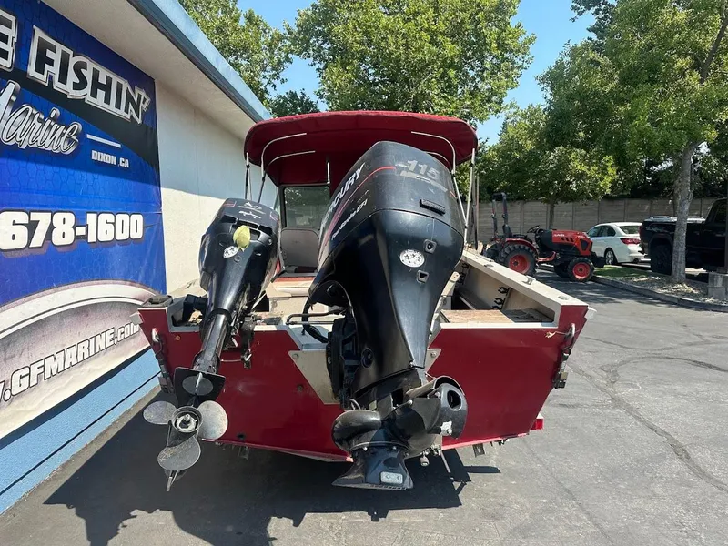 Slide: The Image of 2003 Alumaweld Stryker boat with dual outboard motors, parked near a marine shop. - 9