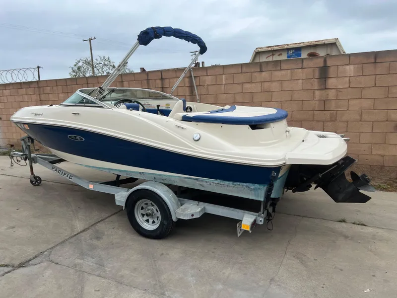 Slide: The Image of 2007 Sea Ray 185 Sport boat on trailer, blue and white design, parked outdoors. - 4