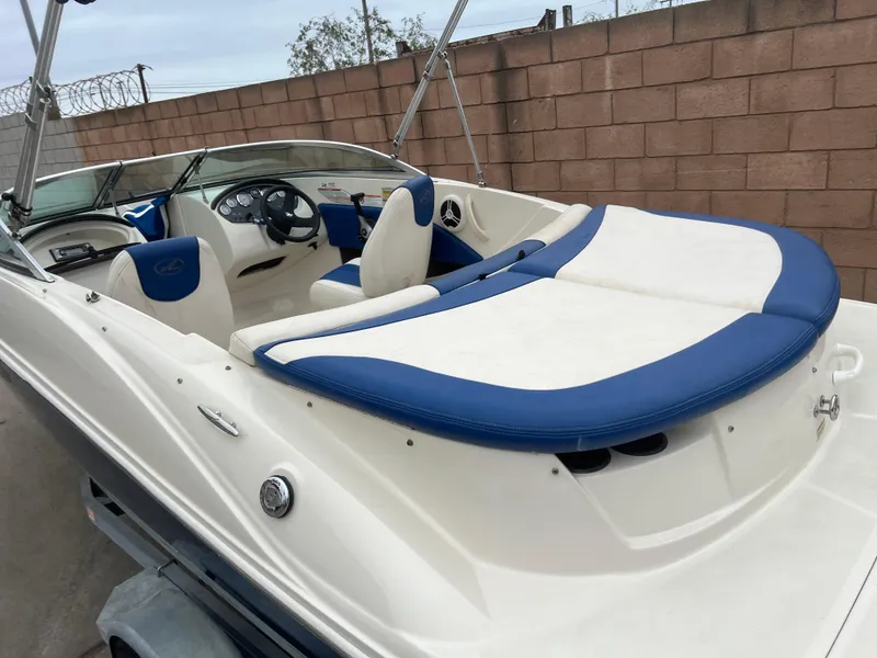Slide: The Image of 2007 Sea Ray 185 Sport boat with blue and white interior, parked near a brick wall. - 5