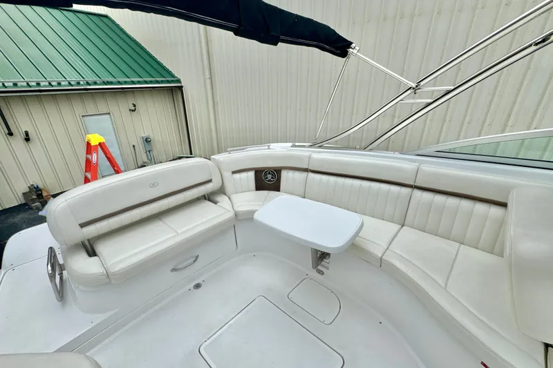 Slide: The Image of 2008 Cobalt 323 boat interior with white seating and small table, docked near a building. - 9