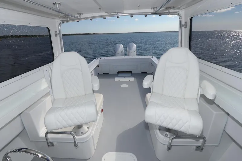 Slide: The Image of 2026 Steiger Craft 31 Fisherman interior with white seating, overlooking calm waters. - 14