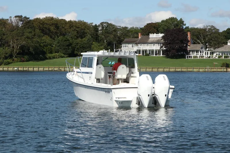 Slide: The Image of 2026 Steiger Craft 31 Fisherman boat on calm water near a large house. - 6