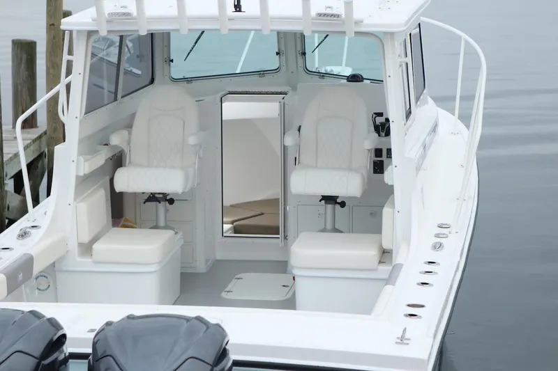 Slide: The Image of 2026 Steiger Craft 28 Miami boat interior with white seating and helm, docked on calm water. - 19