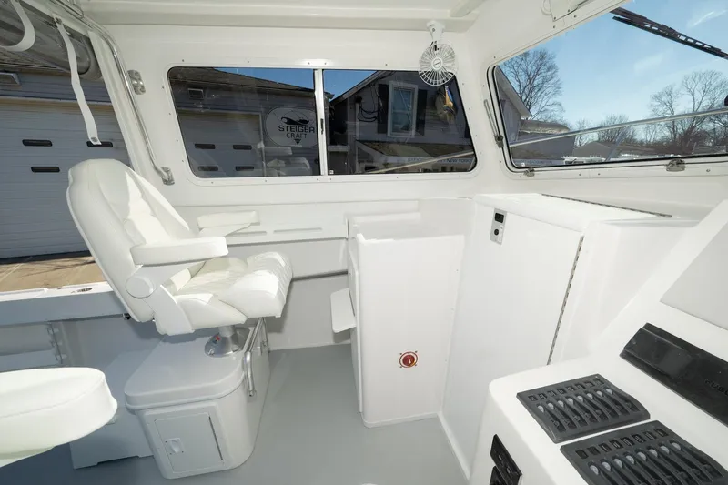 Slide: The Image of 2026 Steiger Craft 28 Fisherman interior with white seating and control panel. - 10