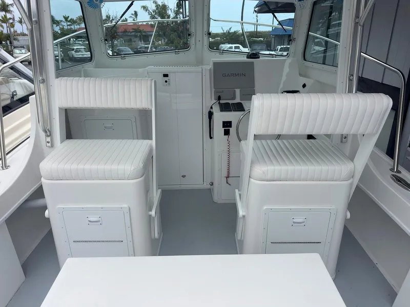 Slide: The Image of 2026 Steiger Craft 28 Hawaii boat interior with white seating and Garmin navigation system. - 27