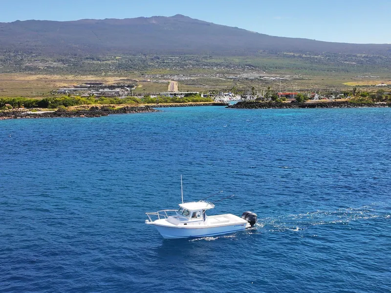 Slide: The Image of 2026 Steiger Craft 28 Hawaii boat cruising in clear blue waters near a scenic coastline. - 9