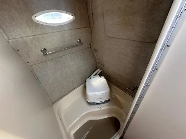 Slide: The Image of 1997 Sea Ray 240 Sundancer boat bathroom with compact toilet and small window. - 12