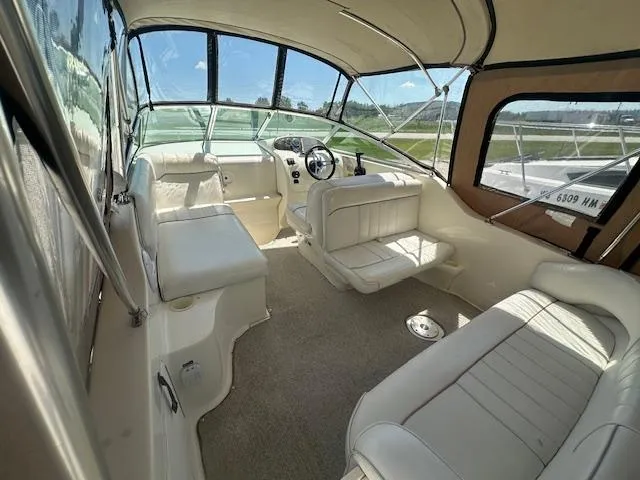 Slide: The Image of 1997 Sea Ray 240 Sundancer interior with white seating and helm, featuring large windows. - 6