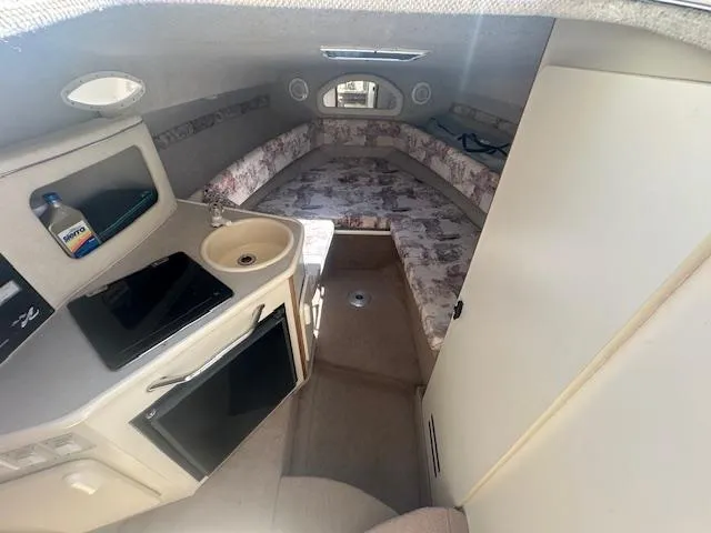 Slide: The Image of 1997 Sea Ray 240 Sundancer cabin interior with kitchenette, sink, and cozy sleeping area. - 9