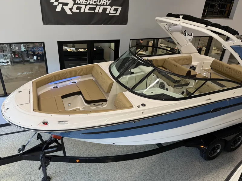 Slide: The Image of 2025 Sea Ray SDX250 Surf boat on display in showroom with Mercury Racing banner. - 12