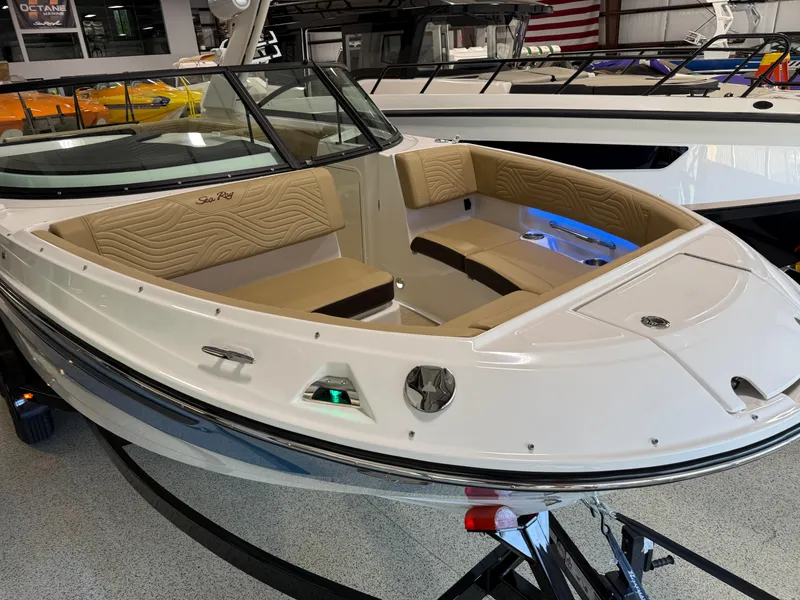 Slide: The Image of 2025 Sea Ray SDX250 Surf boat with tan seating and sleek design in showroom. - 15