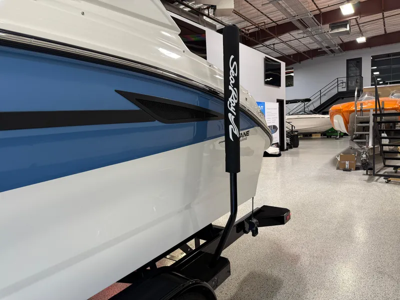 Slide: The Image of 2025 Sea Ray SDX250 Surf boat in showroom, blue and white exterior. - 2