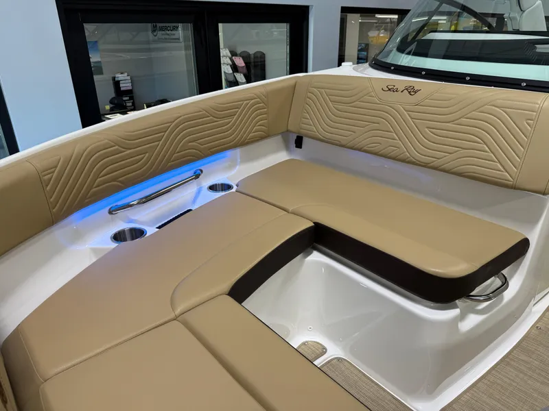 Slide: The Image of 2025 Sea Ray SDX250 Surf boat interior with tan seating and blue LED lighting. - 21