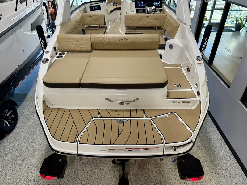 Slide: The Image of 2025 Sea Ray SDX250 Surf boat interior with beige seating and teak-style flooring. - 31