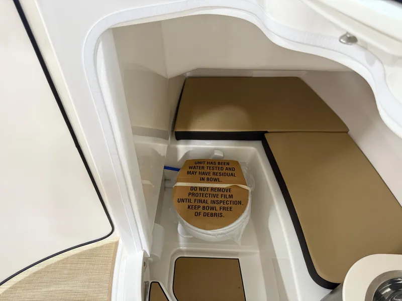 Slide: The Image of 2025 Sea Ray SDX250 Surf interior storage compartment with protective film and warning label. - 49
