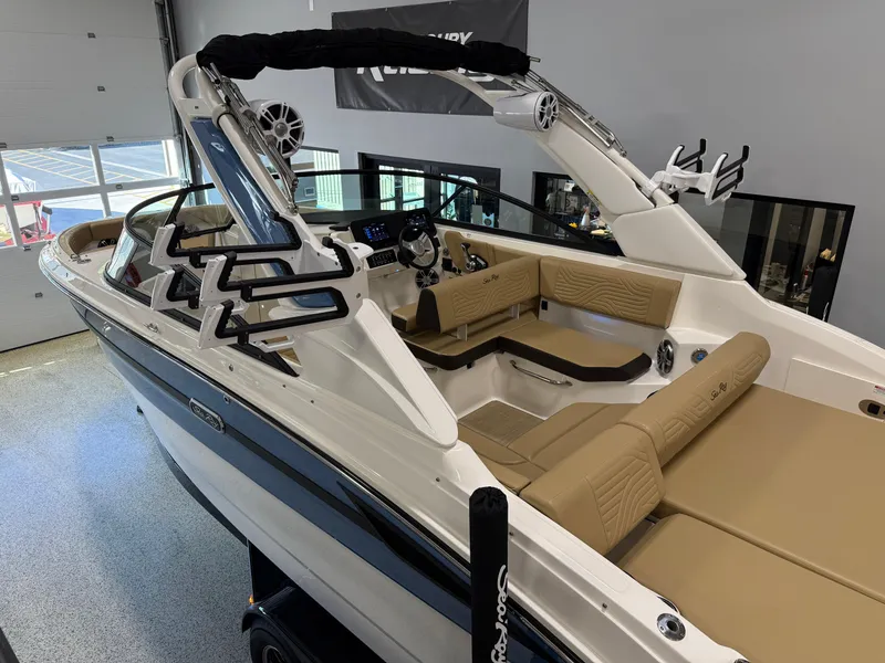 Slide: The Image of 2025 Sea Ray SDX250 Surf boat with tan seating and sleek design in showroom. - 5