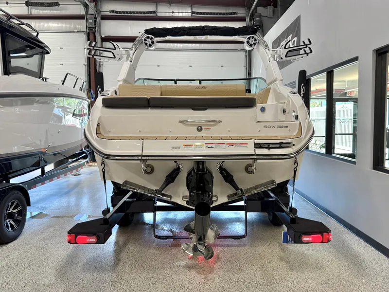 Slide: The Image of 2025 Sea Ray SDX250 Surf boat in showroom, rear view with propeller and trailer. - 8