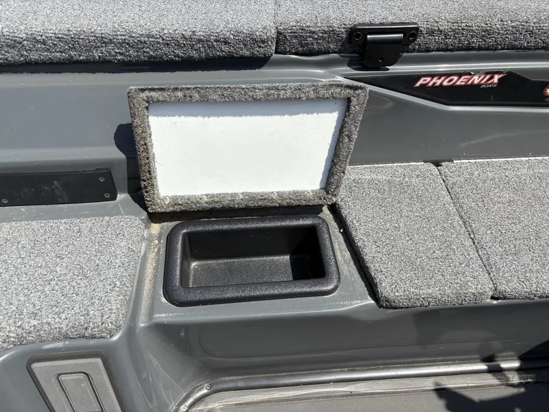 Slide: The Image of 2023 Phoenix 920 Elite boat interior with open storage compartment and carpeted surfaces. - 13