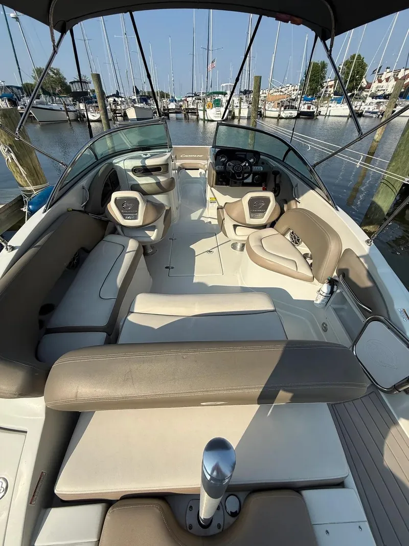 Slide: The Image of 2023 Crownline Eclipse E235 XS boat interior at marina, featuring spacious seating and helm. - 14