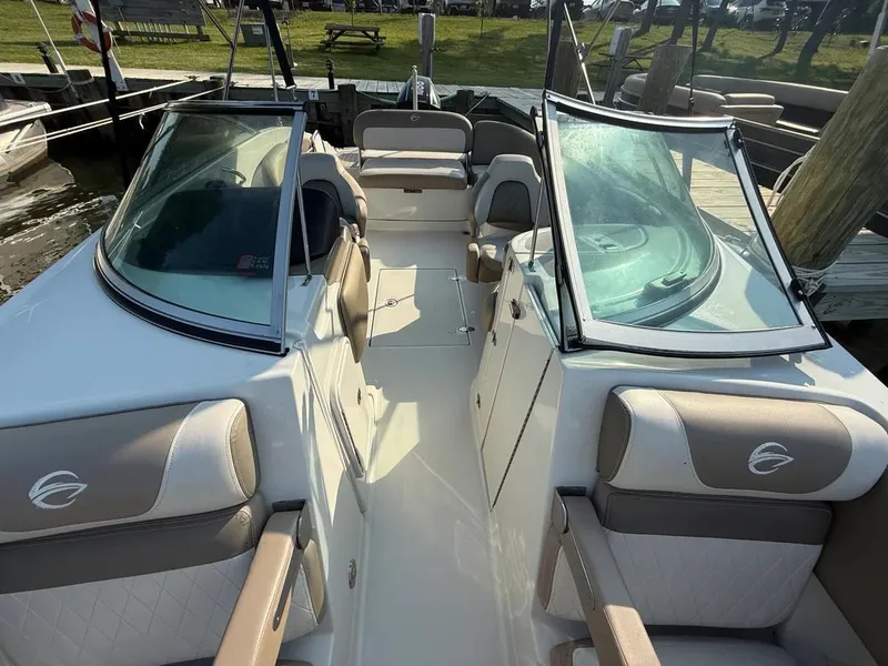 Slide: The Image of 2023 Crownline Eclipse E235 XS boat interior with seating and windshield, docked at marina. - 17