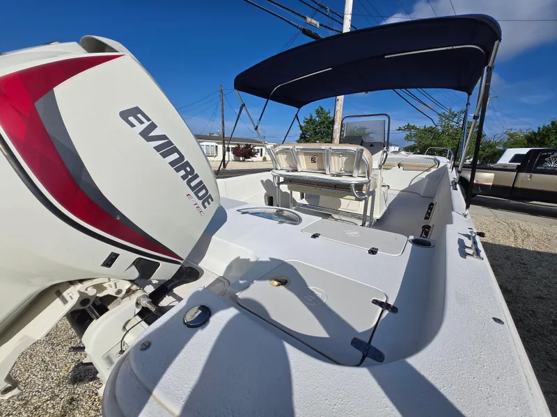 Slide: The Image of 2016 Carolina Skiff 238 DLV boat with Evinrude engine and canopy, parked outdoors. - 5
