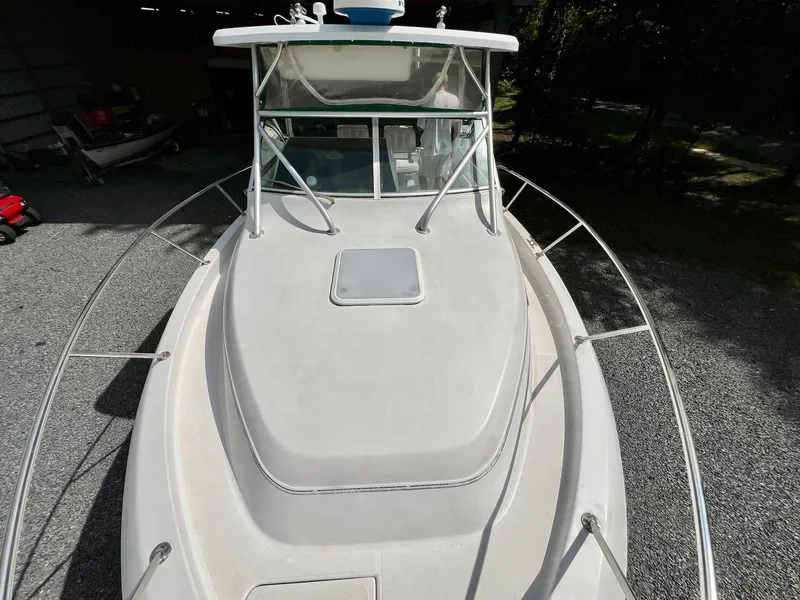 Slide: The Image of 1997 Pro-Line 2810 Walkaround boat, top view, showing deck and cabin, parked on gravel. - 10