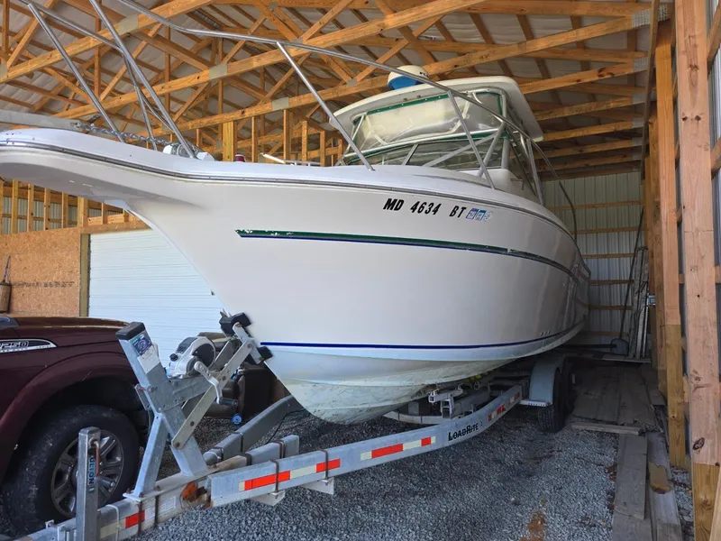 Slide: The Image of 1997 Pro-Line 2810 Walkaround boat on trailer in a wooden storage shed. - 2