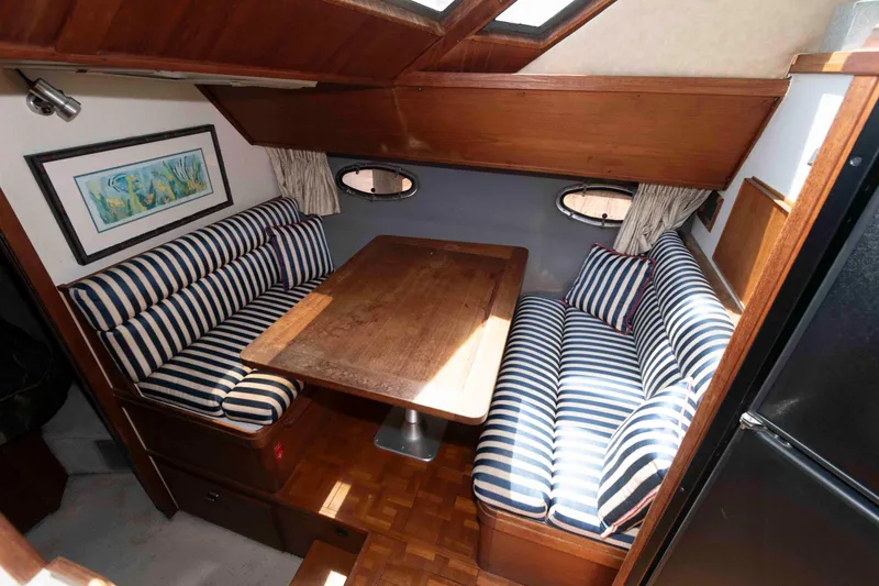 Slide: The Image of 1989 Tiara Yachts 36 Convertible interior with striped seating and wooden table. - 11